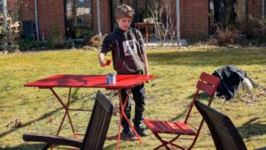 Junge lackiert Gartenmöbel rot
