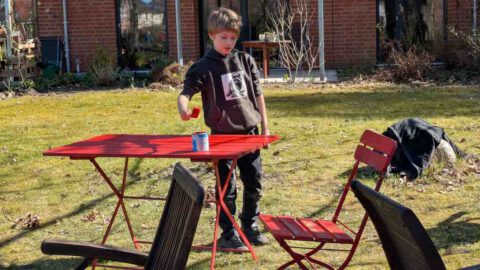 Junge lackiert Gartenmöbel rot