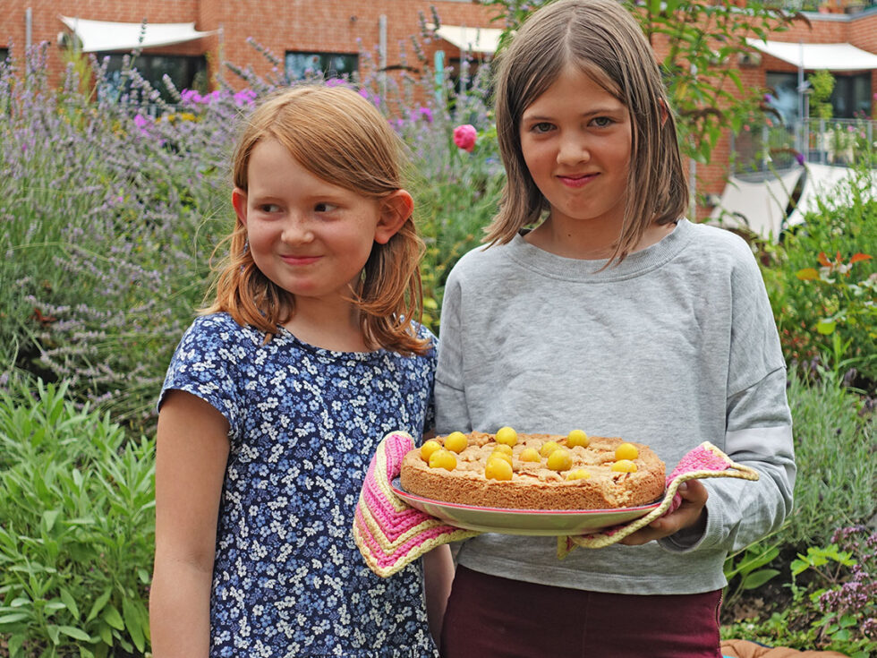 Zwei Mädchen präsentieren stolz ihren selbst gebackenen Mirabellenkuchen