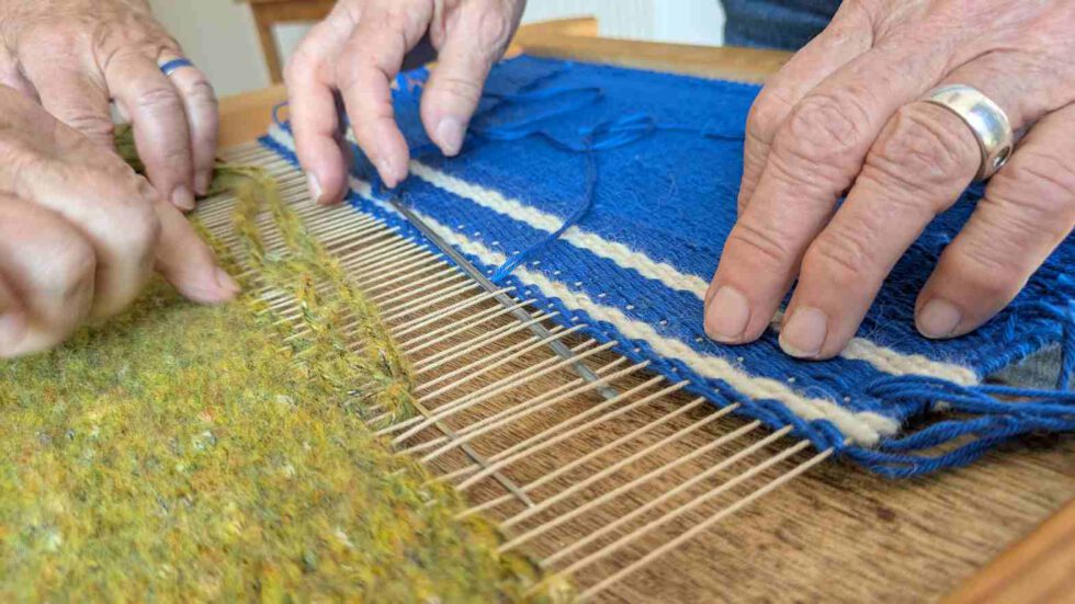 Hände arbeiten am Webrahmen groß