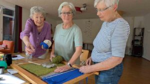 3 Frauen am Webrahmen arbeiten gemeinsam an Webbild