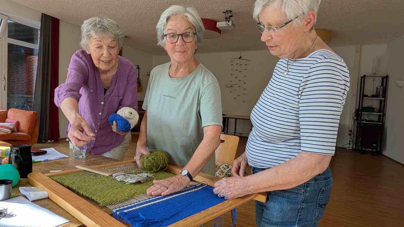 3 Frauen am Webrahmen arbeiten gemeinsam an Webbild