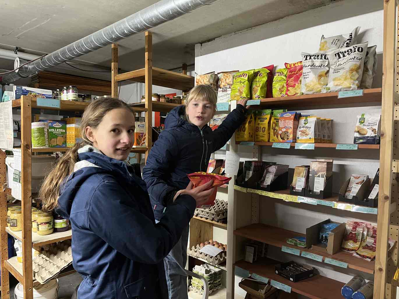 2 junge Mädchen beim Einkauf am Regal mit Chips und Schokolade