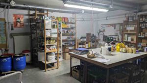 LeNa-Foodcoop - Totale des Raums mit Regalen, Tisch, Fässern etc. voller Angebote