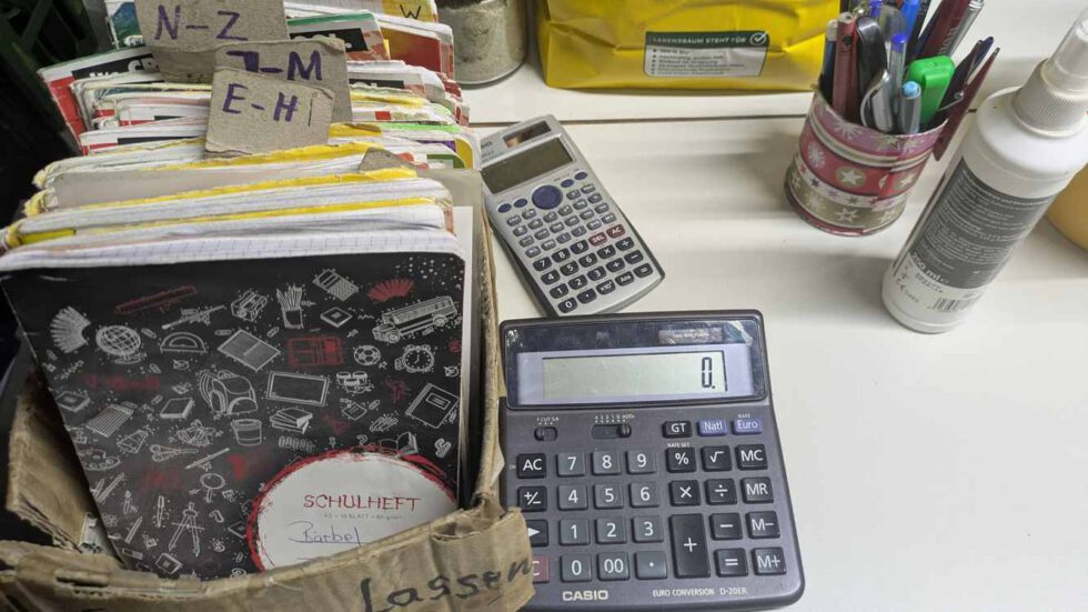 LeNa-Foodcoop - Tisch mit Rechner und Stiften und Schachtel mit Kontoheften